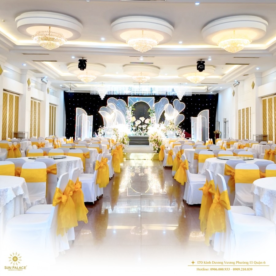 Toàn cảnh sảnh tiệc cưới sang trọng tại Sun Palace với ghế phủ nơ vàng và sân khấu hoa tươi lộng lẫy