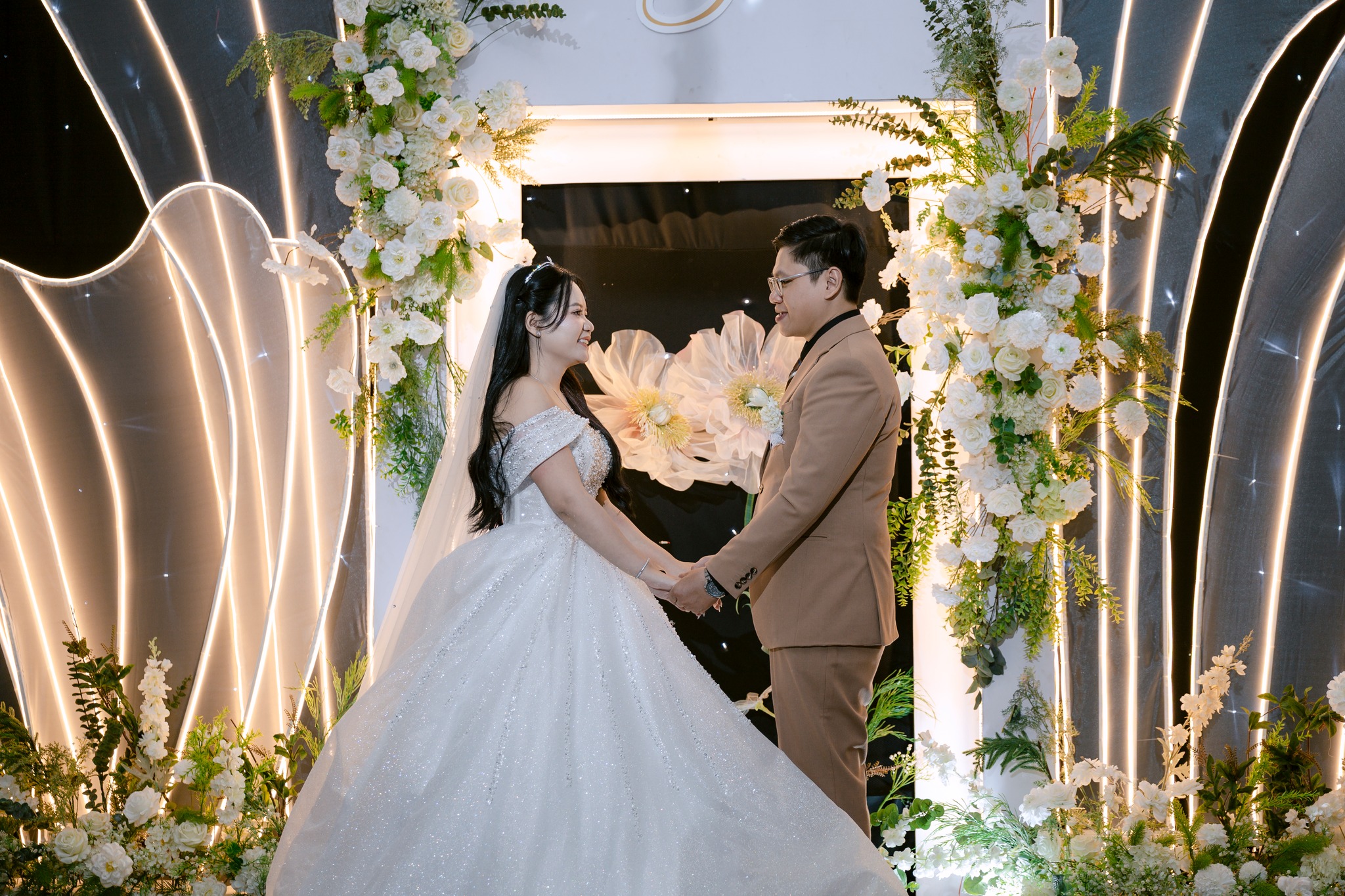 cô dâu chú rể nắm tay trên sân khấu