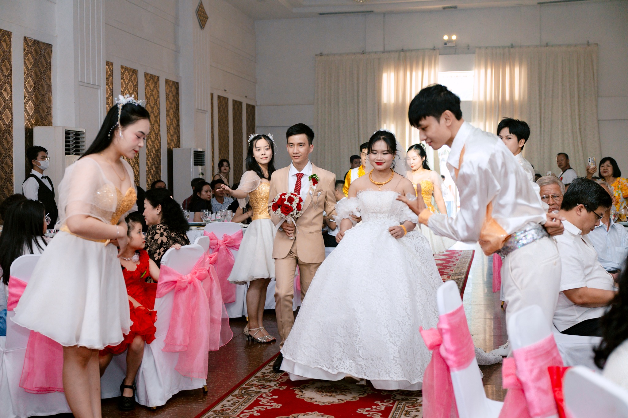 cô dâu chú rể nắm tay nhau bước lên sân khấu