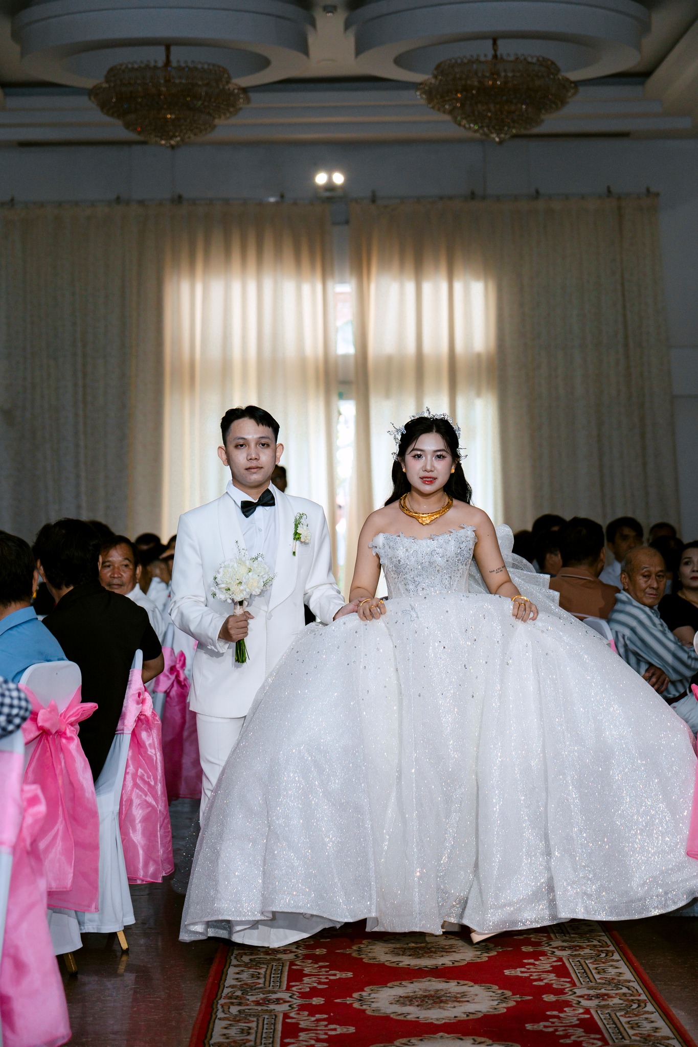 cô dâu chú rể nắm tay nhau bước trên lễ đường