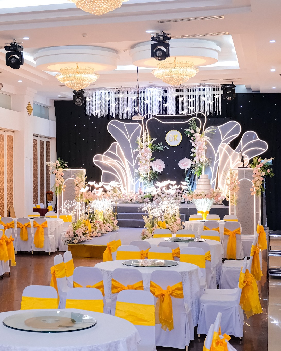 Tiệc cưới với ghế nơ vàng nổi bật và sân khấu hoa ánh sáng ấn tượng tại trung tâm tiệc cưới Sun Palace